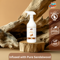 Gleamsure Mysore Sandalwood Room Freshener bottle placed on a natural wooden block with a driftwood backdrop, representing earthy sandalwood essence.